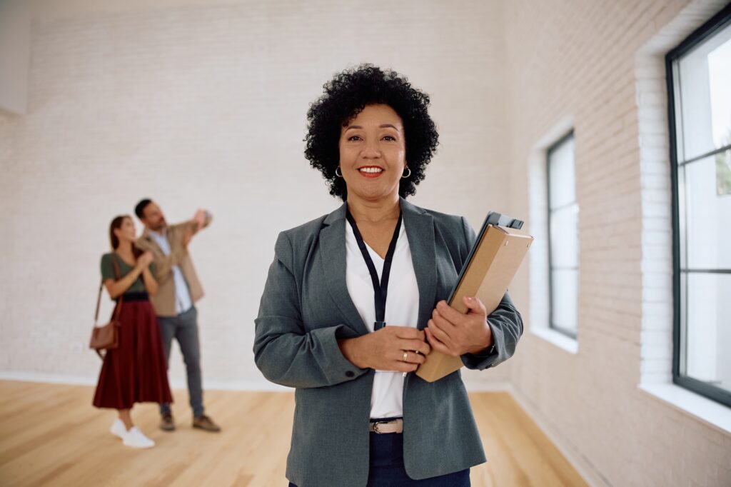 Portrait of real estate agent with her clients in the background.